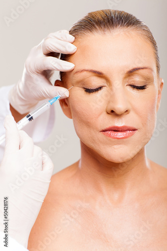 cosmetic surgeon injecting mid age woman