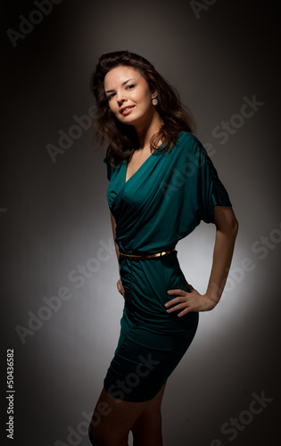 Beautiful girl in a green dress on a dark background.
