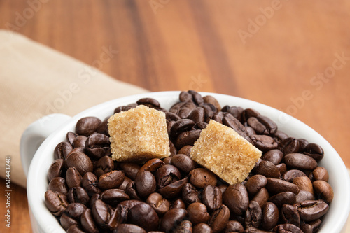 heap of coffee beans in cup with cane-sugar