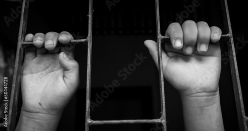 hands of a girl are grabbing steel cage