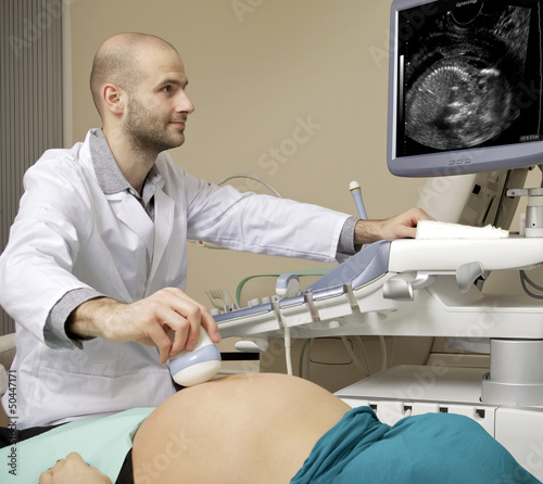 Portrait of young male technician operating ultrasound machine