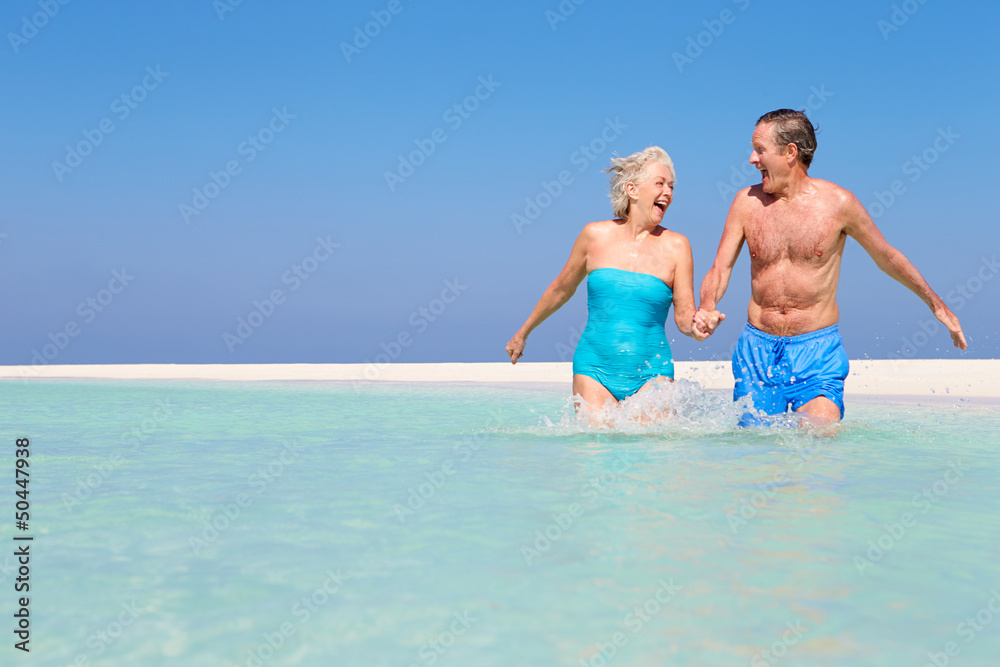 Senior Couple Having Fun In Sea On Beach Holiday