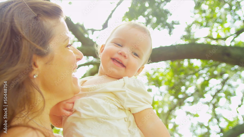 Caucasian smiling mother holding happy kid in garden