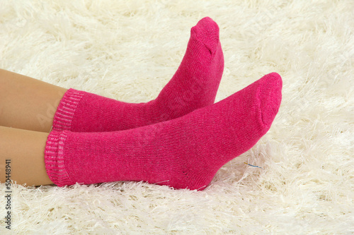 Female legs in colorful socks on  white carpet background