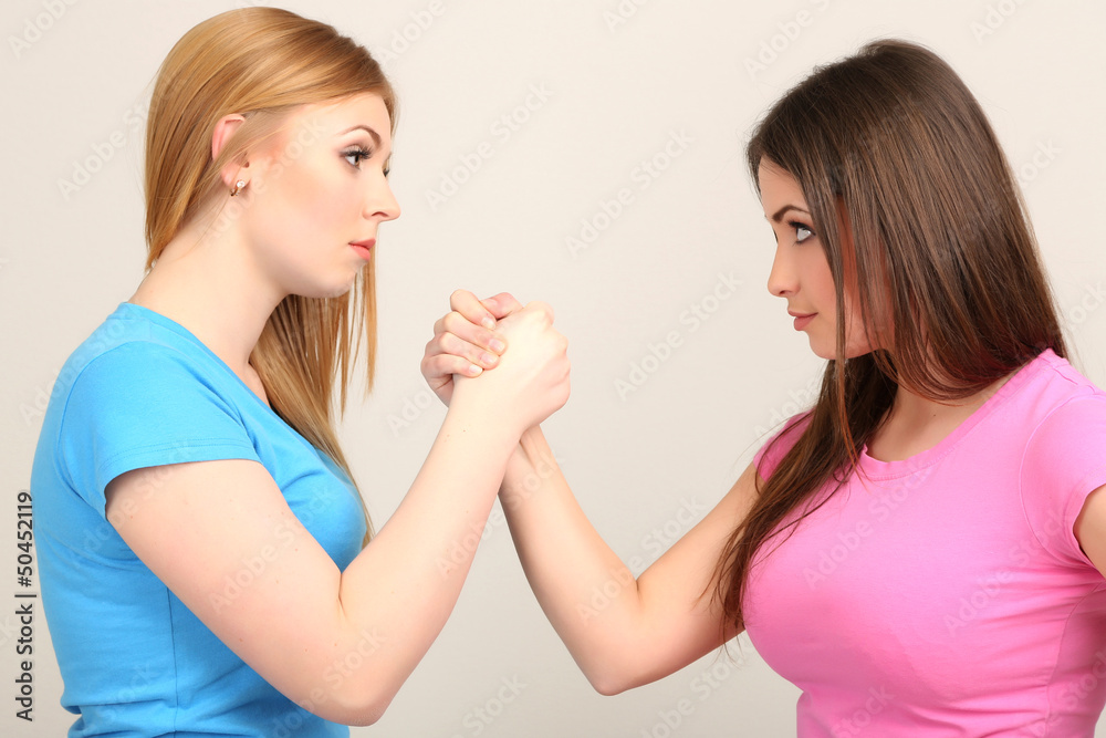 Two girl friends quarrel on grey background Two girl friends quarrel on grey background