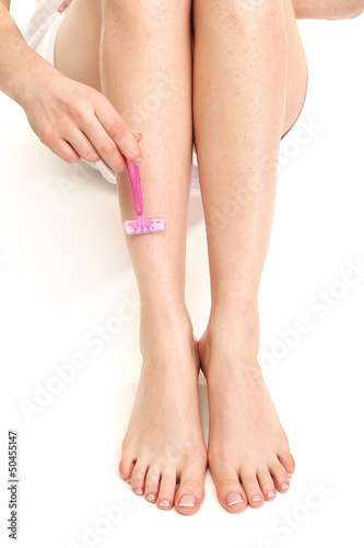 Beautiful woman is shaving her leg, isolated on white © Africa Studio
