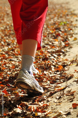 Woman walking cross country trail in autumn forest