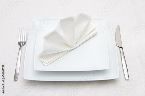 Place setting with white plates and white folded napkin
