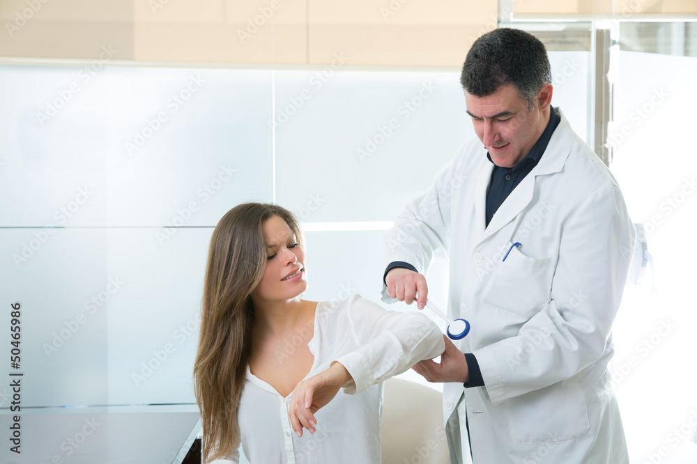 Doctor checking elbow with reflex round hammer to woman Doctor checking elbow with reflex round hammer to woman