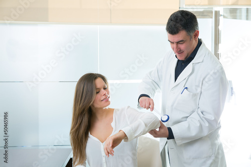 Doctor checking elbow with reflex round hammer to woman