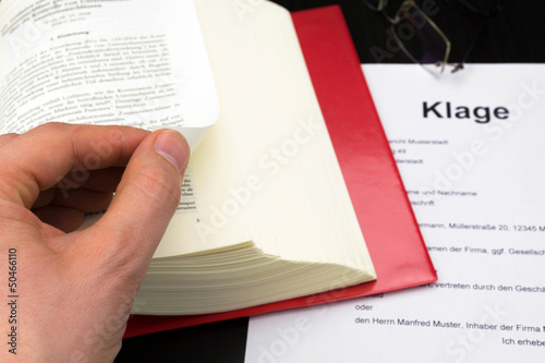 Klage mit Buch, Hand und Brille