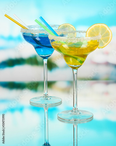 Yellow and blue cocktails in glasses on blue natural background
