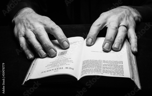 A man reading the Holy Bible with two hands.