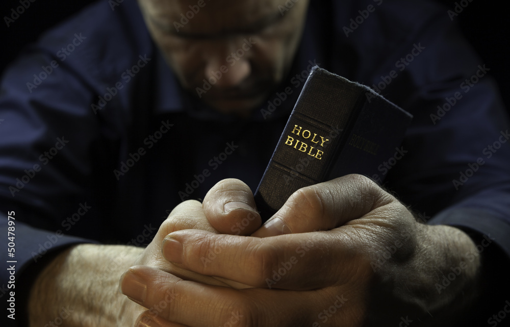 © Duncan Andison - A Man praying holding a Holy Bible.