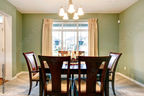 Green dining room interior with classic brown furniture.