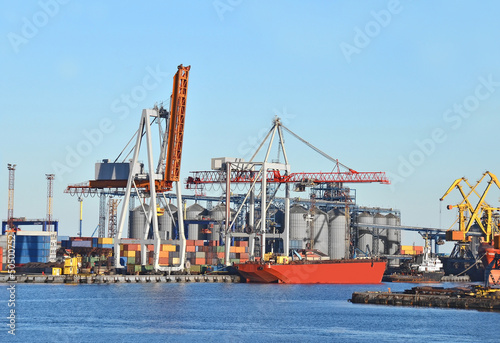 Container stack and ship under crane bridge © Unkas Photo