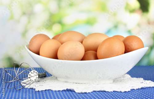 Eggs in white bowl on blue tablecloth close-up