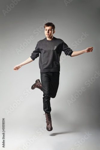 Young fashion male jumping on grey background