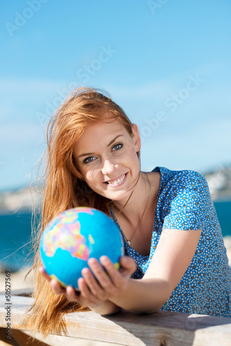 lachende junge frau mit globus am meer