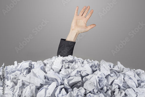 The hand reaches out from big heap of crumpled papers photo