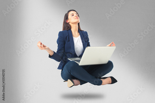 Young businesswoman sitting in yoga lotus position with laptop