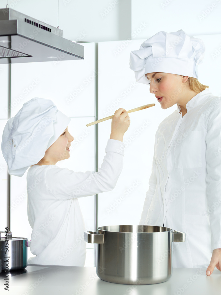 Mother and child having fun in the kitchen to taste a soup