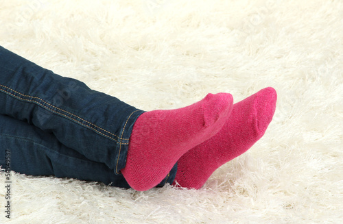 Female legs in colorful socks on  white carpet background
