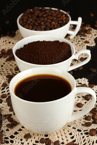 Different types of coffee in three cups on wooden table