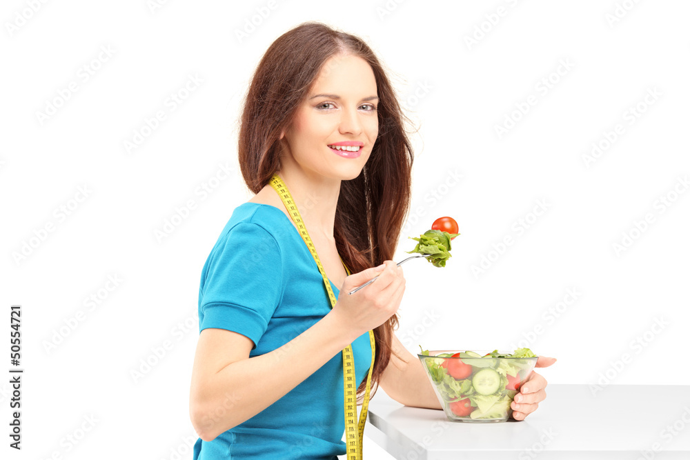 Young woman sitting and eating a fresh salad Young woman sitting and eating a fresh salad