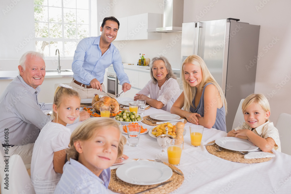 Father cutting turkey and looking at camera