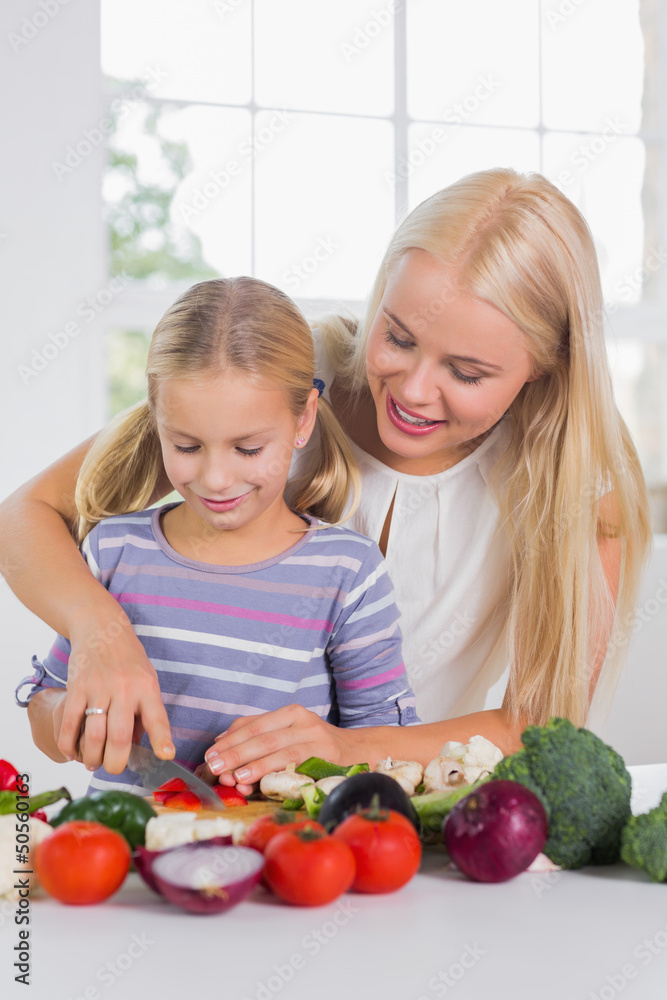 Focused mother teaching cutting vegetables Focused mother teaching cutting vegetables