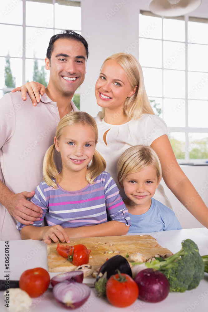Posing family cutting vegetables together Posing family cutting vegetables together