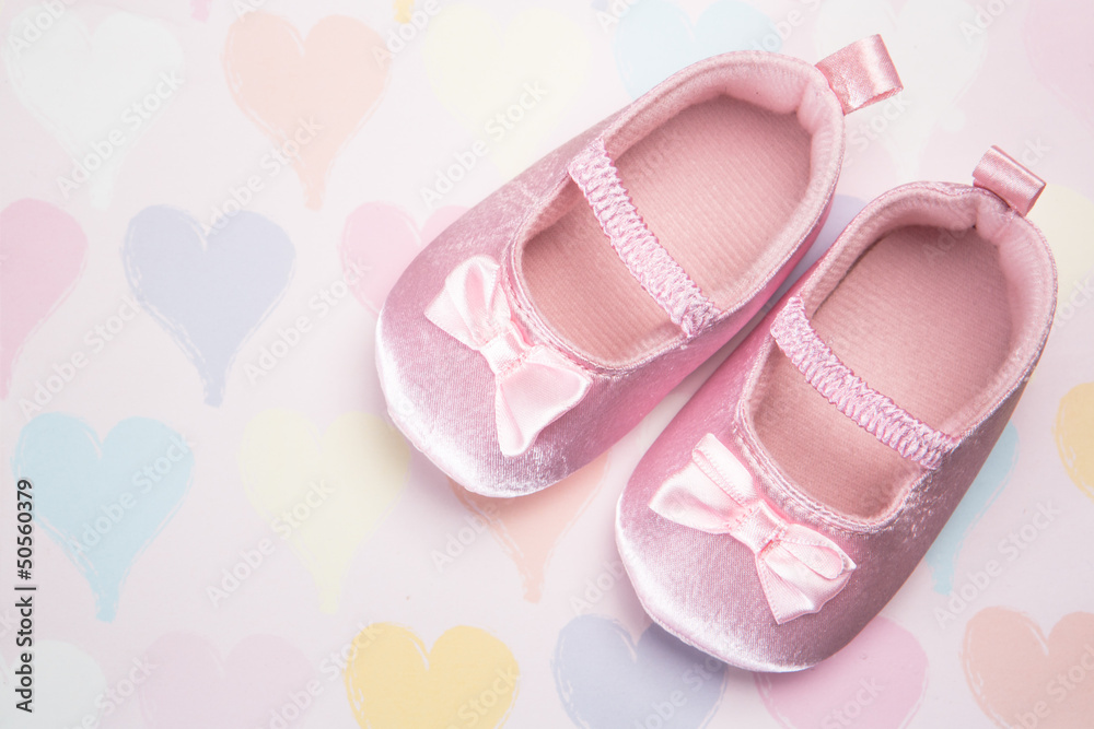 Baby pink booties on heart pattern background Baby pink booties on heart pattern background