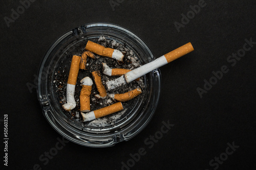 Burning cigarette left in ashtray photo