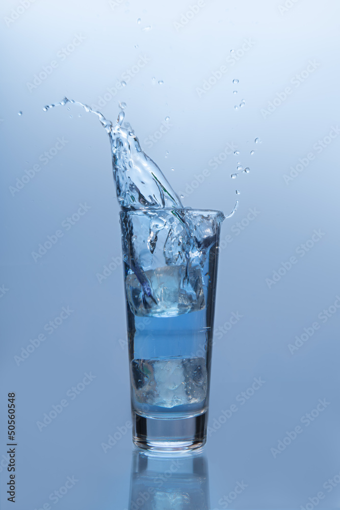 An ice cube falling into glass of water An ice cube falling into glass of water