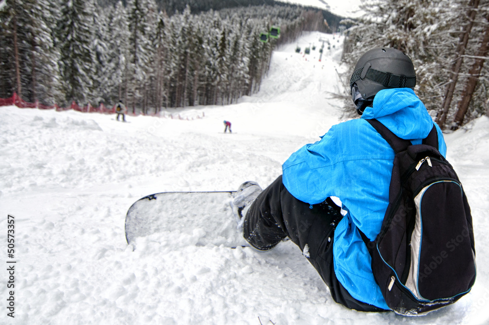 Rear view of sportsman with snowboard looking down on difficult
