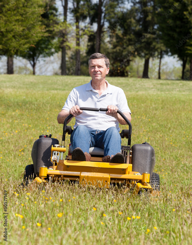 Fototapeta premium Senior man on zero turn lawn mower on turf