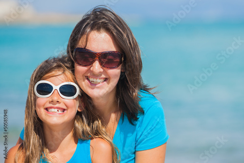 Mother and her daughter in sunglasses on beach