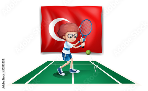 A boy playing tennis in front of the flag of Turkey