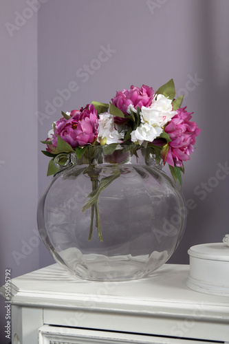 artivicial pink and white peony in glass vase standing on table