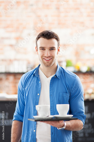 Waiter holding cups of coffee in cafe
