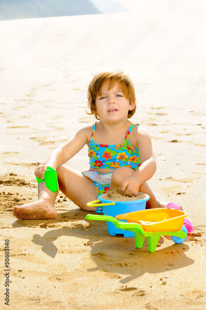 Happy toddler girl playing with her toys on the beach Happy toddler girl playing with her toys on the beach