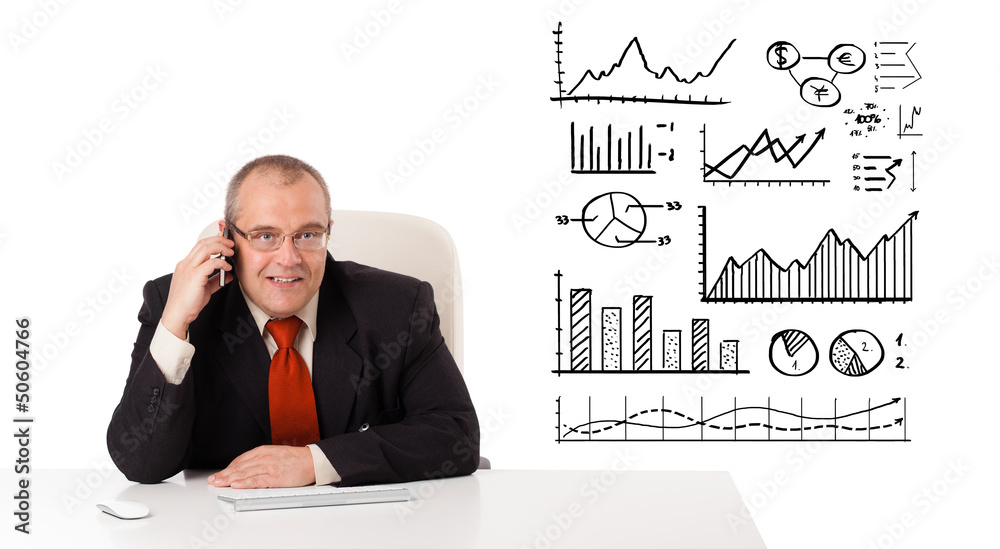 Businessman sitting at desk with diagrams and making a phone cal