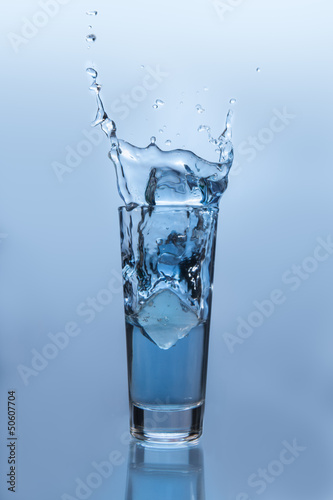 Ice cube falling into glass of water