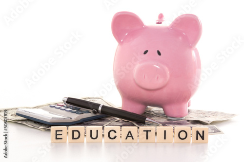 Piggy bank beside calculator and education spelled out in plasti photo