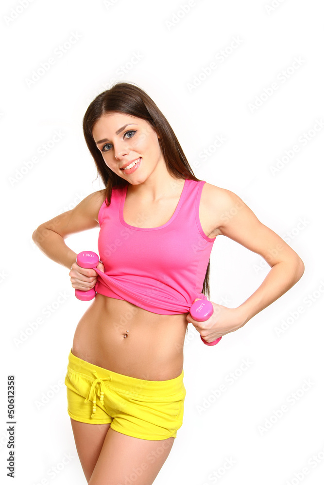 Cute fitness girl with dumbbells showing her belly on white back Cute fitness girl with dumbbells showing her belly on white back
