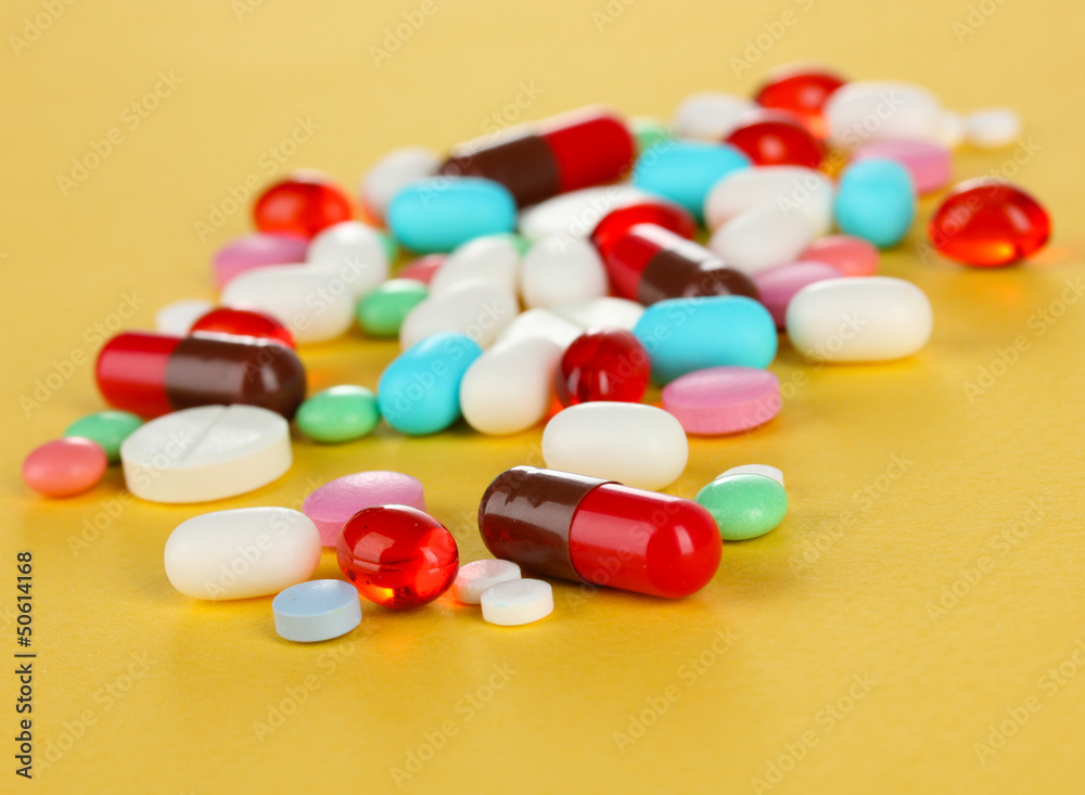 Assortment of pills, tablets and capsules on yellow background Assortment of pills, tablets and capsules on yellow background