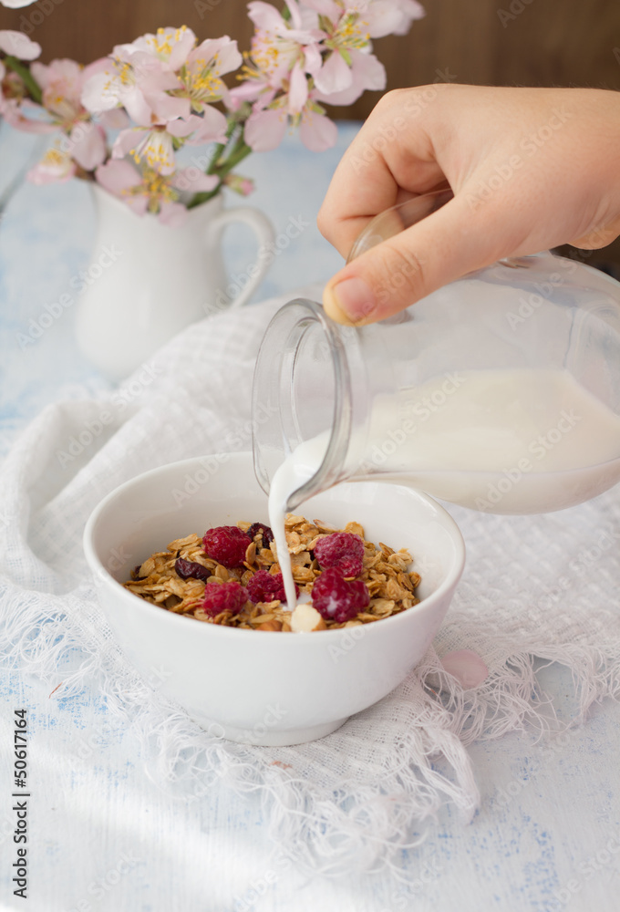 Milk pouring onto muesli with raspberry Milk pouring onto muesli with raspberry