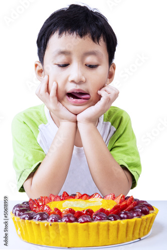 Little boy with fruit cake on white