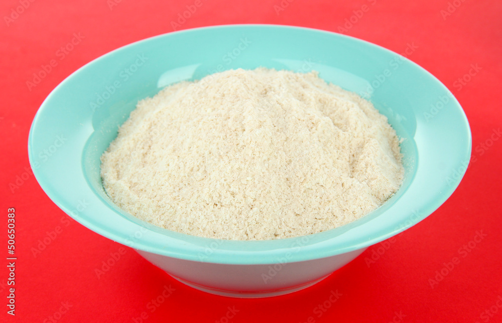 Powdered milk in bowl for baby on red background Powdered milk in bowl for baby on red background